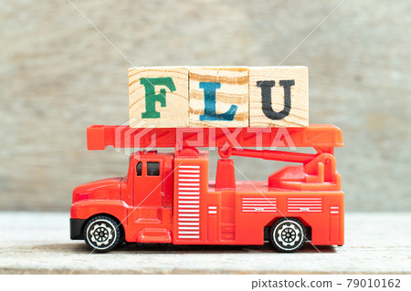 Fire ladder truck hold letter block in word flu on wood background Fire ladder truck hold letter block in word flu on wood background 79010162
