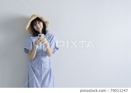 A woman wearing a straw hat using a smartphone A woman wearing a straw hat using a smartphone 79011247