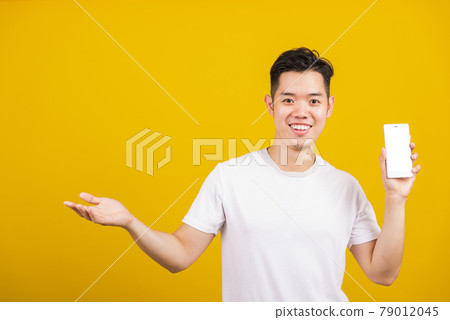young man smiling positive showing mobile phone blank screen with another hand palm open empty space 79012045