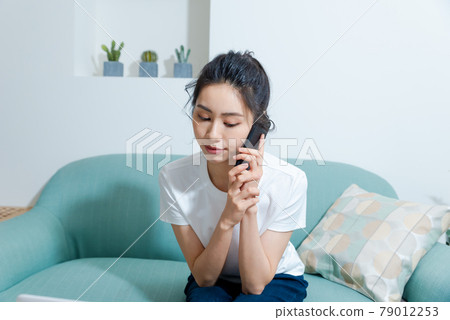 Beautiful girl working on computer in living room at home Beautiful girl working on computer in living room at home 79012253