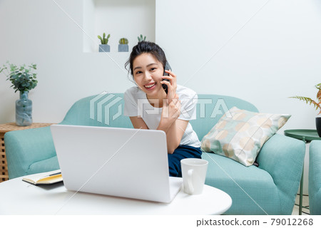 Beautiful girl sitting on the sofa and playing computer Beautiful girl sitting on the sofa and playing computer 79012268