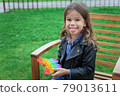 Caucasian little girl playing with pop it silicone trendy rainbow colow toy 79013611