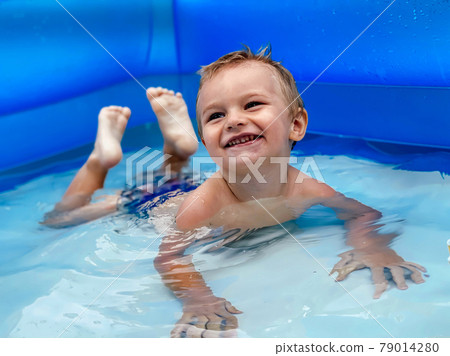 A small child in an inflatable kids round pool in sunny summer weather A small child in an inflatable kids round pool in sunny summer weather 79014280