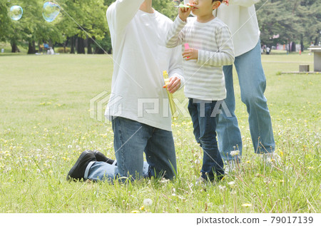 Family playing soap bubbles in the park Family playing soap bubbles in the park 79017139