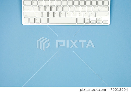 Compact white wireless keyboard on a blue background. Copy space. Compact white wireless keyboard on a blue background. Copy space. 79018904