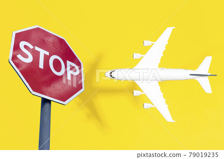 Flight ban and closed borders for tourists and travelers. No-fly zone concept. Airplane in flight with a STOP sign 79019235