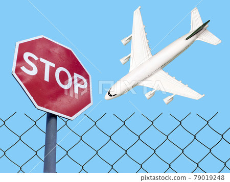 Flight ban and closed borders for tourists and travelers. No-fly zone concept. Airplane in flight with a STOP sign 79019248