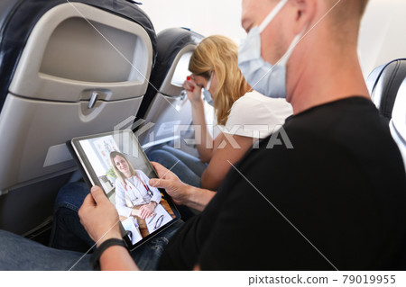 Man receives medical advice on video call while sitting on airplane Man receives medical advice on video call while sitting on airplane 79019955