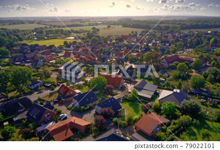 Oblique aerial view of a village in Germany with detached houses, yarns, lawns and roads 79022101