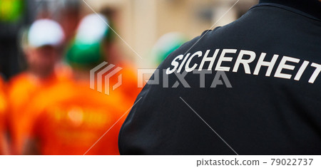 Back view of a man with a black waistcoat with the German inscription "Sicherheit" (Translation: security) Back view of a man with a black waistcoat with the German inscription "Sicherheit" (Translation: security) 79022737