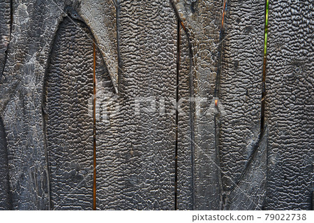 Abstract image of a wooden wall that has been completely evenly charred by a fire, as texture or background. Abstract image of a wooden wall that has been completely evenly charred by a fire, as texture or background. 79022738