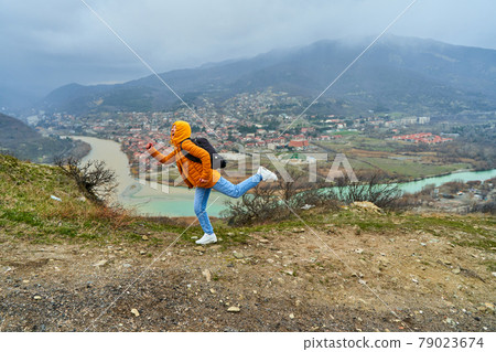 Young girl tourist rejoices posing against the backdrop of an amazing natural landscape. The confluence of two rivers in the city of Mtskheta in Georgia Young girl tourist rejoices posing against the backdrop of an amazing natural landscape. The confluence of two rivers in the city of Mtskheta in Georgia 79023674