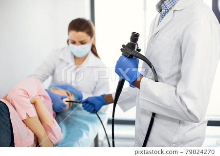 Cropped photo of african man doctor in white coat and rubber gloves standing with a modern endoscope 79024270
