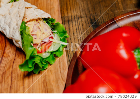 Bell Peppers and pita roll with vegetables and cheese on a wooden cutting board Bell Peppers and pita roll with vegetables and cheese on a wooden cutting board 79024329