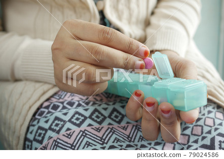 young women taking medicine from a pill box young women taking medicine from a pill box 79024586