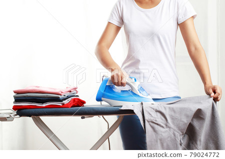 woman is ironing a shirt at home woman is ironing a shirt at home 79024772
