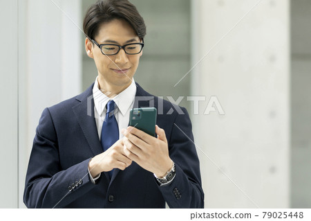 A businessman operating a smartphone 79025448