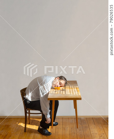 A head of man dropped into a plate with soup on a levitating table 79026535