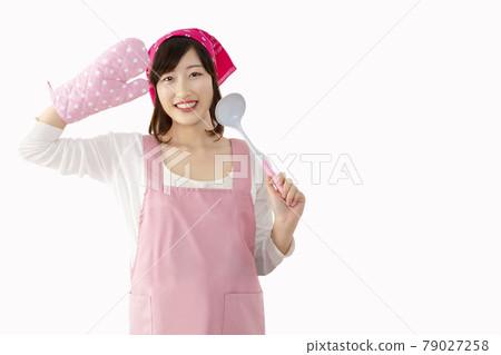 A young woman salutes with a ladle in front of a white background. Image of a woman who cooks cheerfully and cheerfully 79027258