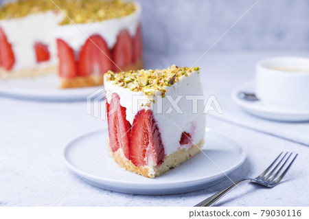 Freesier cake with fresh strawberries and pistachios. French classic dessert. Portion of cake on a white plate close-up. Freesier cake with fresh strawberries and pistachios. French classic dessert. Portion of cake on a white plate close-up. 79030116