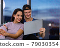 Young couple relaxing and enjoying at home on sofa with laptop. 79030354