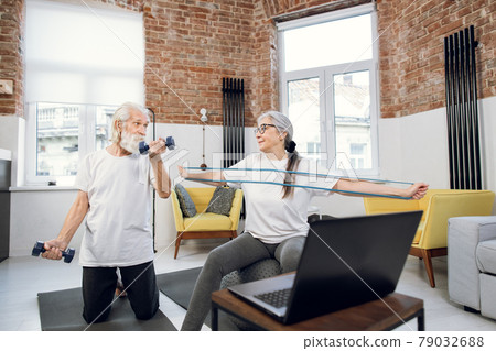 Mature couple watching tutorial on laptop while training Mature couple watching tutorial on laptop while training 79032688