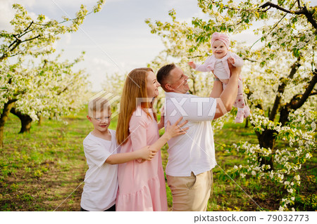 family with son and daughter in spring flowering garden. cleft lip in infants. family with son and daughter in spring flowering garden. cleft lip in infants. 79032773