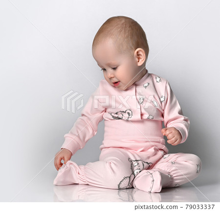 Little cute baby sitting on the floor in the Little cute baby sitting on the floor in the 79033337