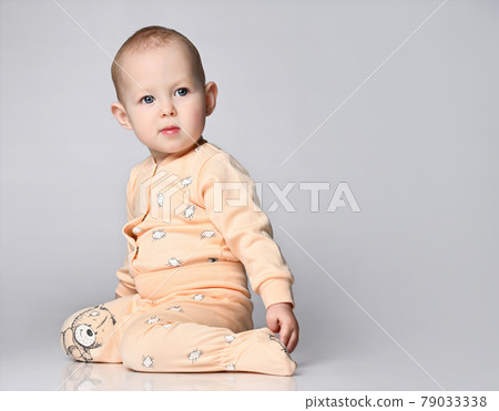 Little cute baby sitting on the floor in the Little cute baby sitting on the floor in the 79033338