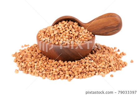 Roasted buckwheat grains in wooden bowl and spoon, isolated on white background. Dry brown buckwheat groats. 79033397