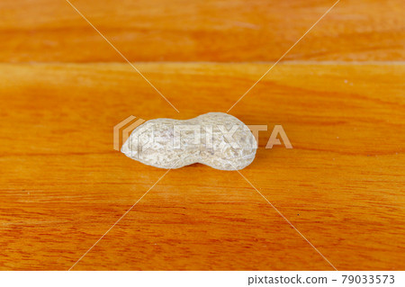 Peanuts on a wooden table. A peanut is placed on a wooden table overlooking the wood grain. 79033573