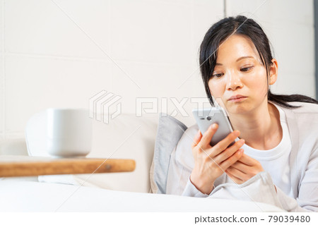 一個女人在客廳裡享受智能手機 一個女人在客廳裡享受智能手機 79039480