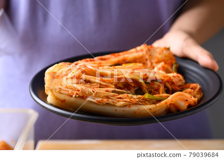 Kimchi cabbage on plate holding by hand, Popular homemade Korean food Kimchi cabbage on plate holding by hand, Popular homemade Korean food 79039684