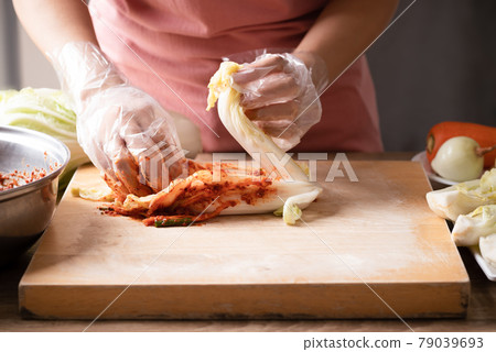 Woman making kimchi cabbage on wooden board, Popular homemade Korean food Woman making kimchi cabbage on wooden board, Popular homemade Korean food 79039693