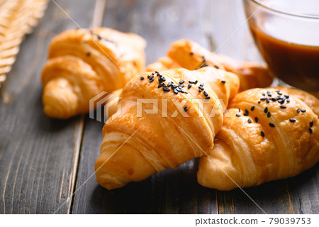 French croissant with black sesame seeds and coffee cup on wooden background, morning breakfast French croissant with black sesame seeds and coffee cup on wooden background, morning breakfast 79039753