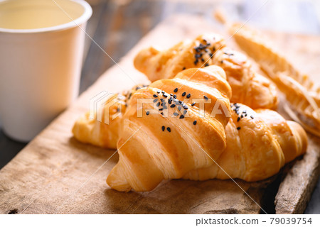 French croissant with black sesame seeds and paper coffee cup on wooden background French croissant with black sesame seeds and paper coffee cup on wooden background 79039754