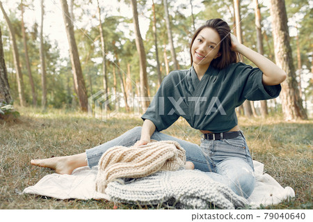 Girl sitting in a summer park and knitting Girl sitting in a summer park and knitting 79040640