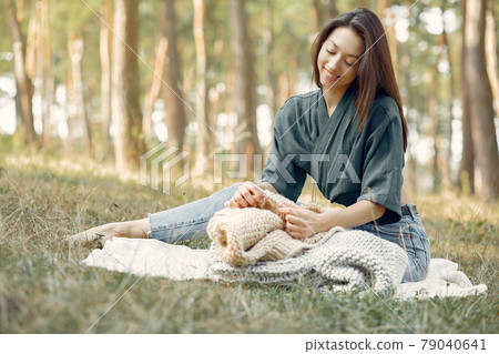 Girl sitting in a summer park and knitting Girl sitting in a summer park and knitting 79040641
