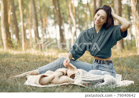 Girl sitting in a summer park and knitting Girl sitting in a summer park and knitting 79040642