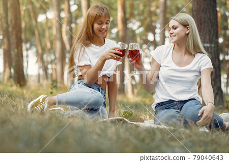 Girls sitting on a picnic and drinking vine Girls sitting on a picnic and drinking vine 79040643