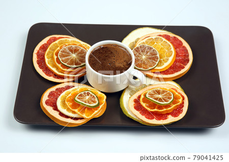 Black coffee in a white Cup surrounded by citrus dried fruits 79041425