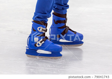 legs of a man in blue skates rides on an ice rink. Hobbies and sports. 79041743