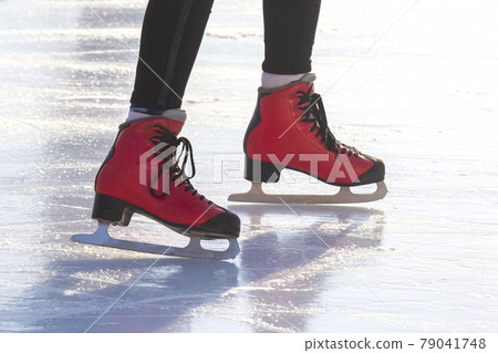 feet in red skates on an ice rink. hobbies and leisure. winter sports 79041748