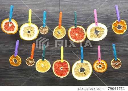 dried pieces of citrus fruits hang on clothespins 79041751