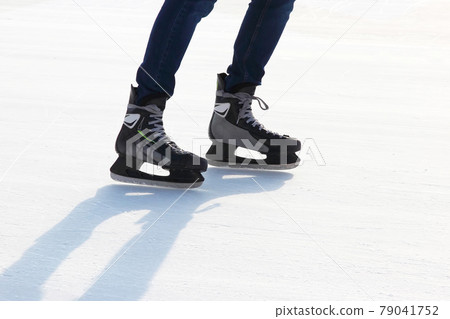 the legs of a man skating on the ice rink 79041752