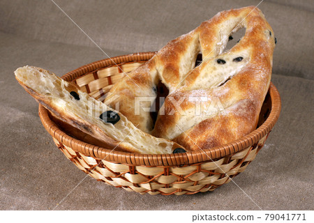 white bread stuffed with olives lies in a straw basket on gray linen tablecloth white bread stuffed with olives lies in a straw basket on gray linen tablecloth 79041771