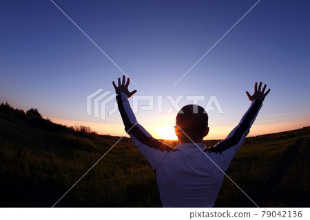 lifted up hands in the background of the sunset 79042136