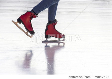 feet in red skates on an ice rink. Hobbies and sports. Vacations and winter activities. feet in red skates on an ice rink. Hobbies and sports. Vacations and winter activities. 79042322