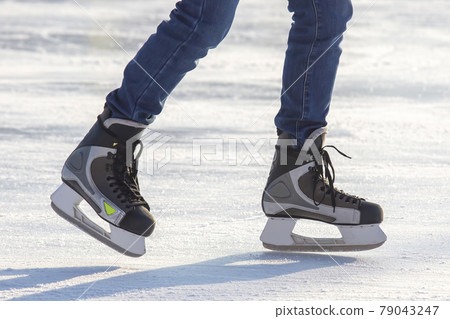 Legs of a skater on ice skating on the street ice rink. winter sport. hobbies and active recreation in sports. Legs of a skater on ice skating on the street ice rink. winter sport. hobbies and active recreation in sports. 79043247