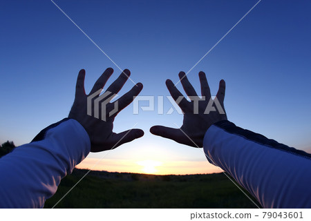 lifted up hands in the background of the sunset. lifted up hands in the background of the sunset. 79043601